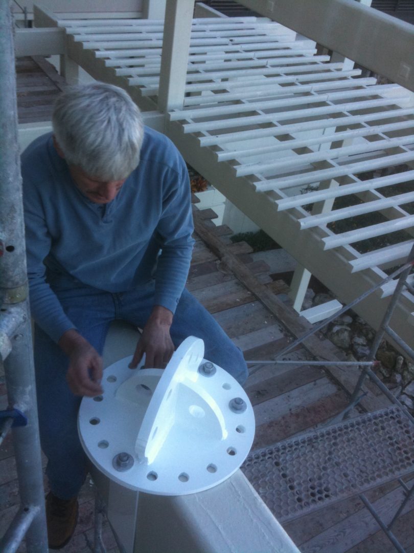 Person assembling or inspecting a white plastic chair outdoors.