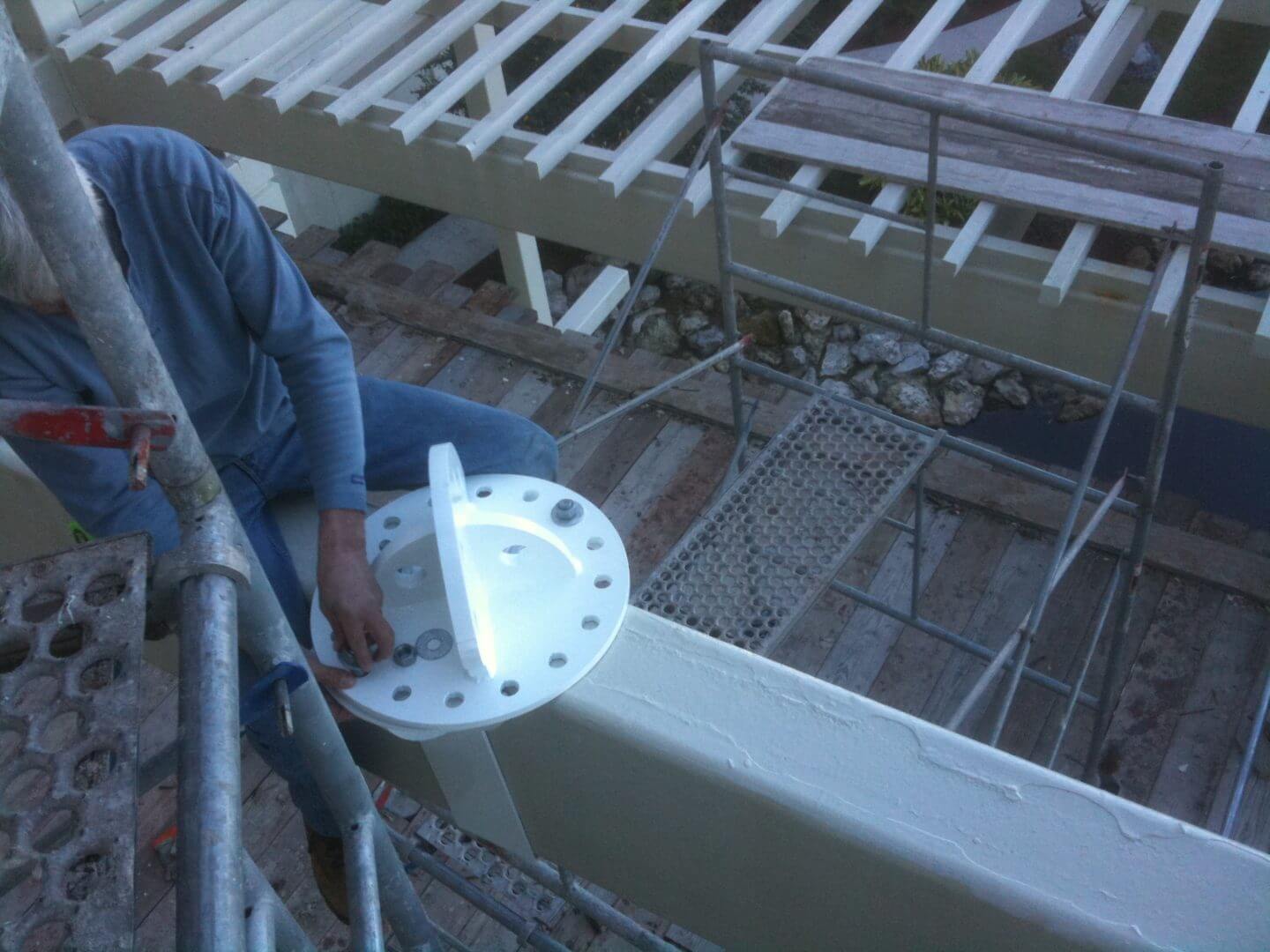 Worker installing a large circular flange on a metal structure.