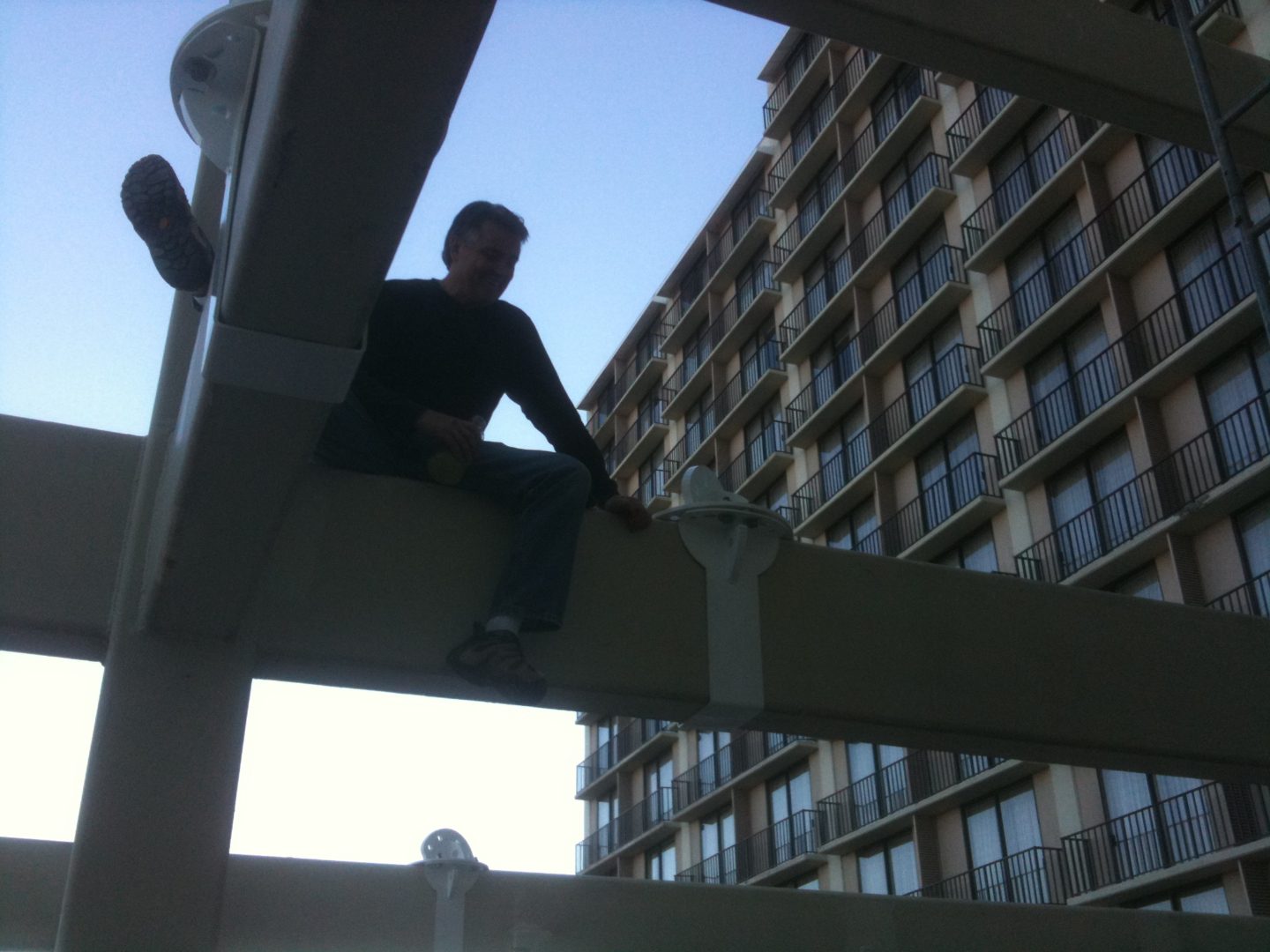 Person sitting on a ledge outside a tall building.