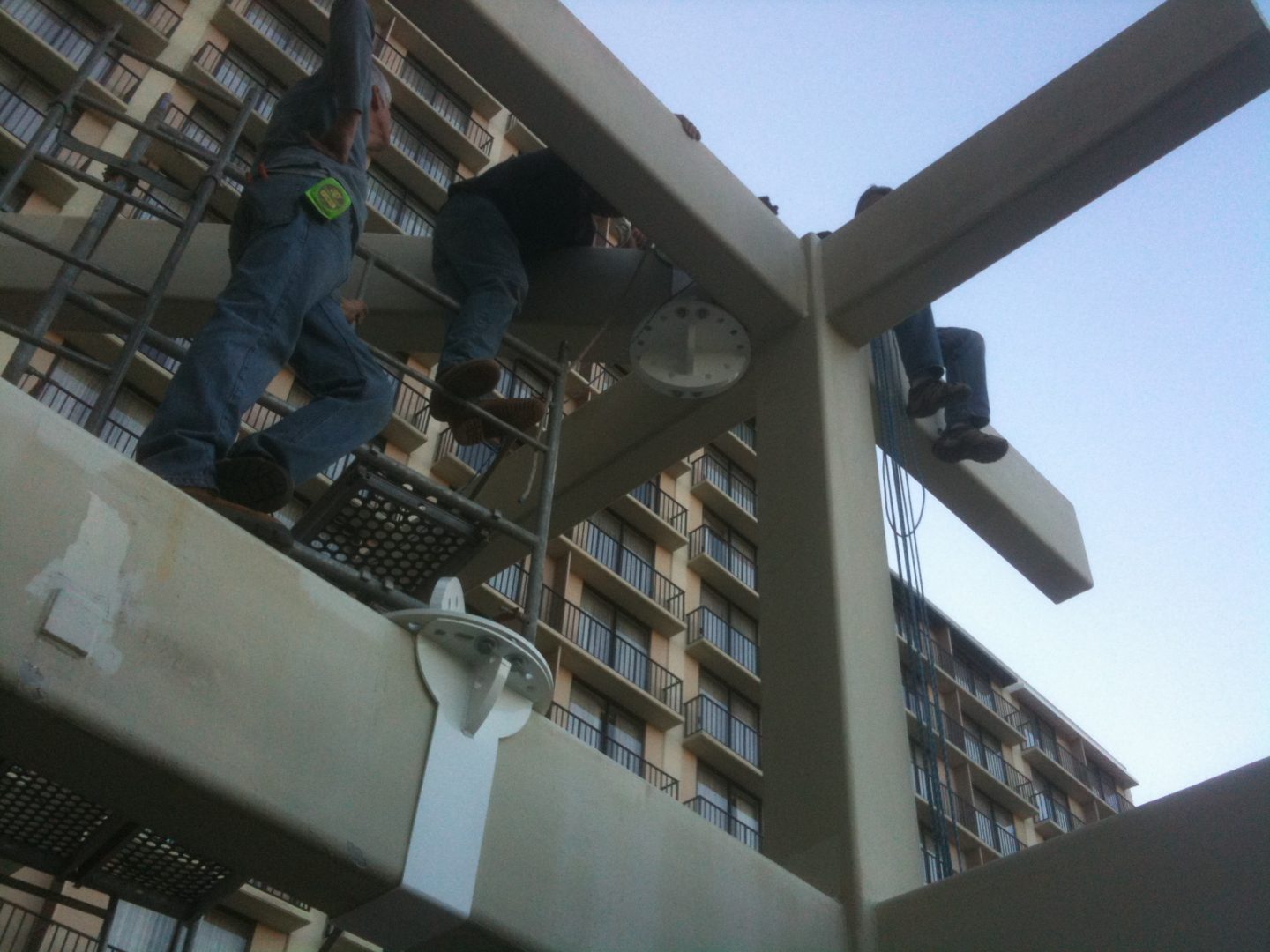 Workers installing or repairing a streetlamp on a building exterior.