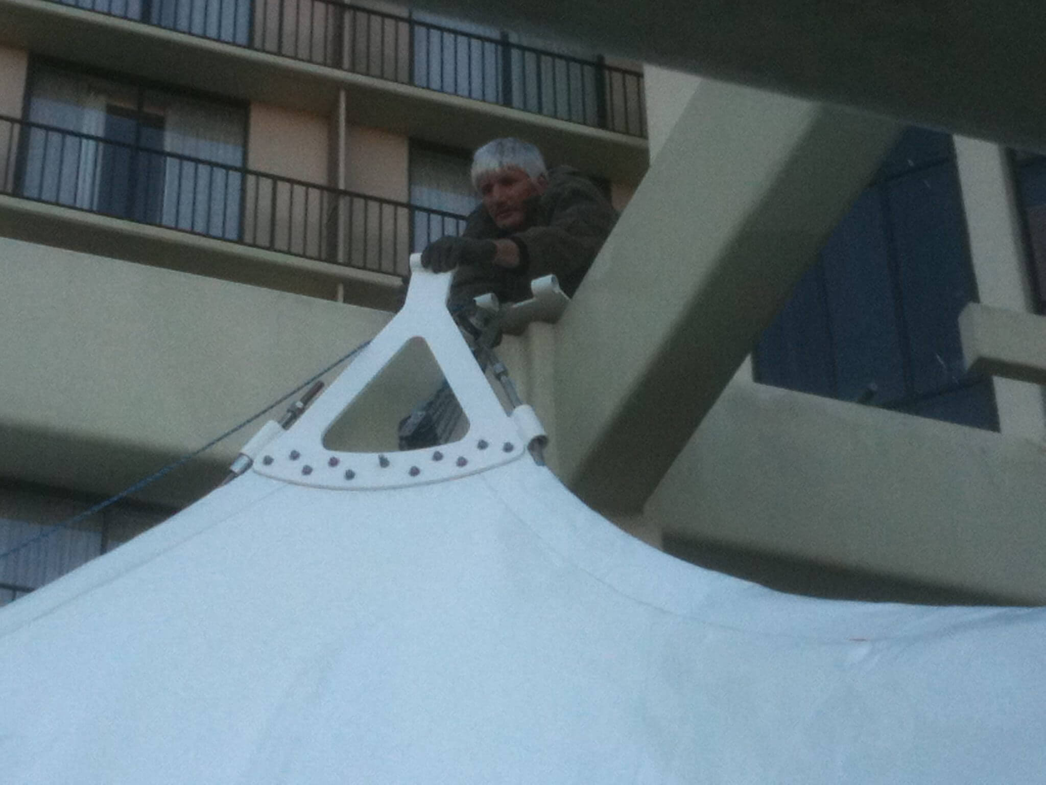 Person leaning over a balcony railing looking down.