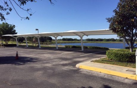 Empty parking lot with solar panel canopies near a lake.