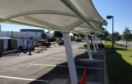 Covered outdoor seating area with benches and tables in a parking lot.