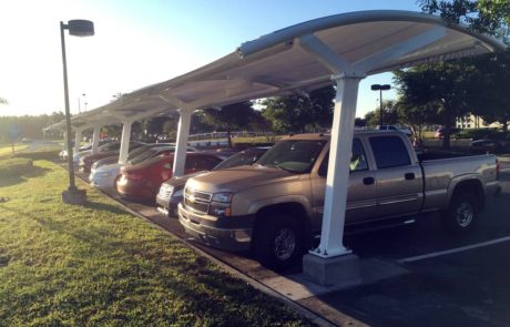 Covered parking area with various parked vehicles during sunset.