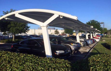 Modern covered parking lot with cars under a white canopy.
