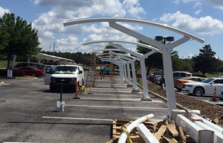 Construction of modern white metal canopy structures in a parking lot.