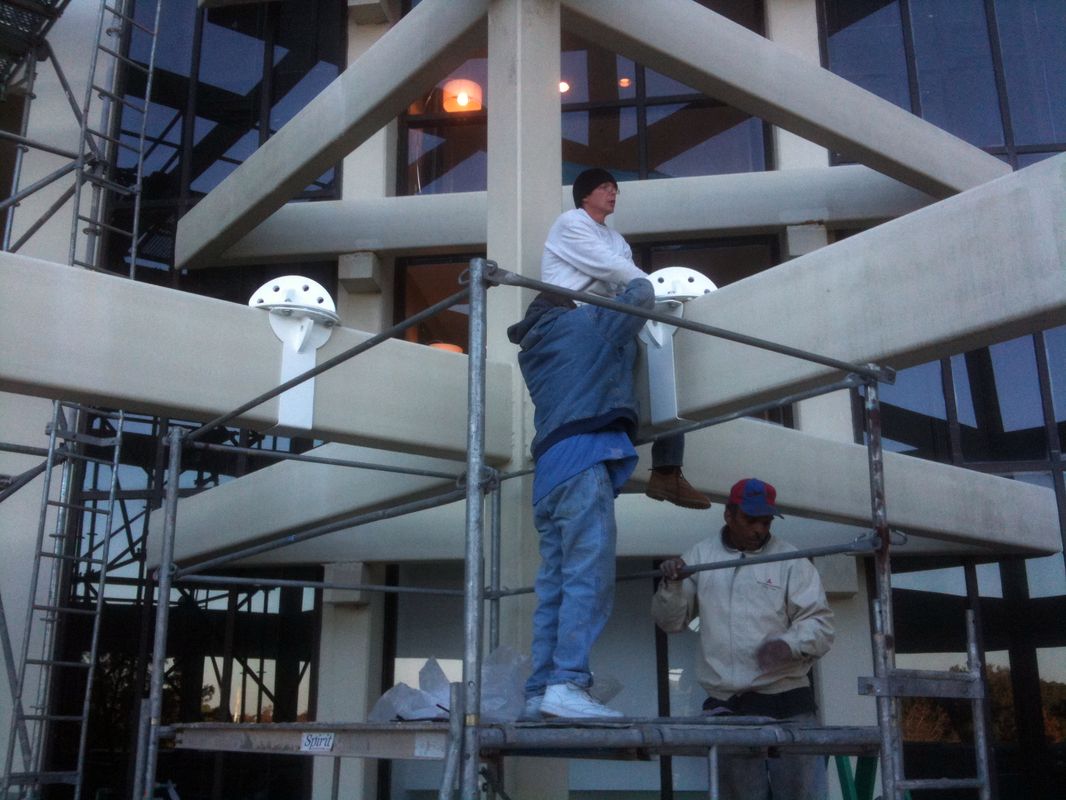 Two workers installing glass panels on building scaffolding.