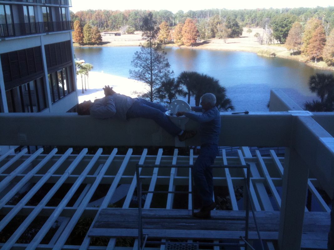 Worker on a roof near a lake, surrounded by trees in autumn.