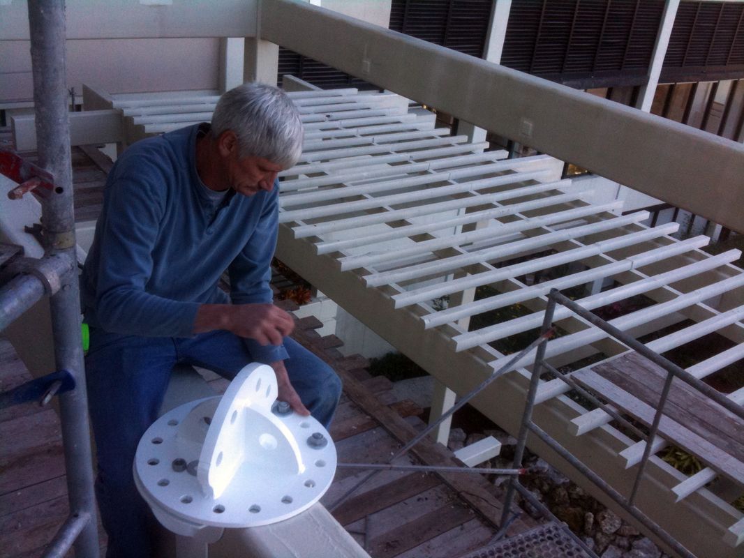 Man working on a white mechanical part in a workshop.