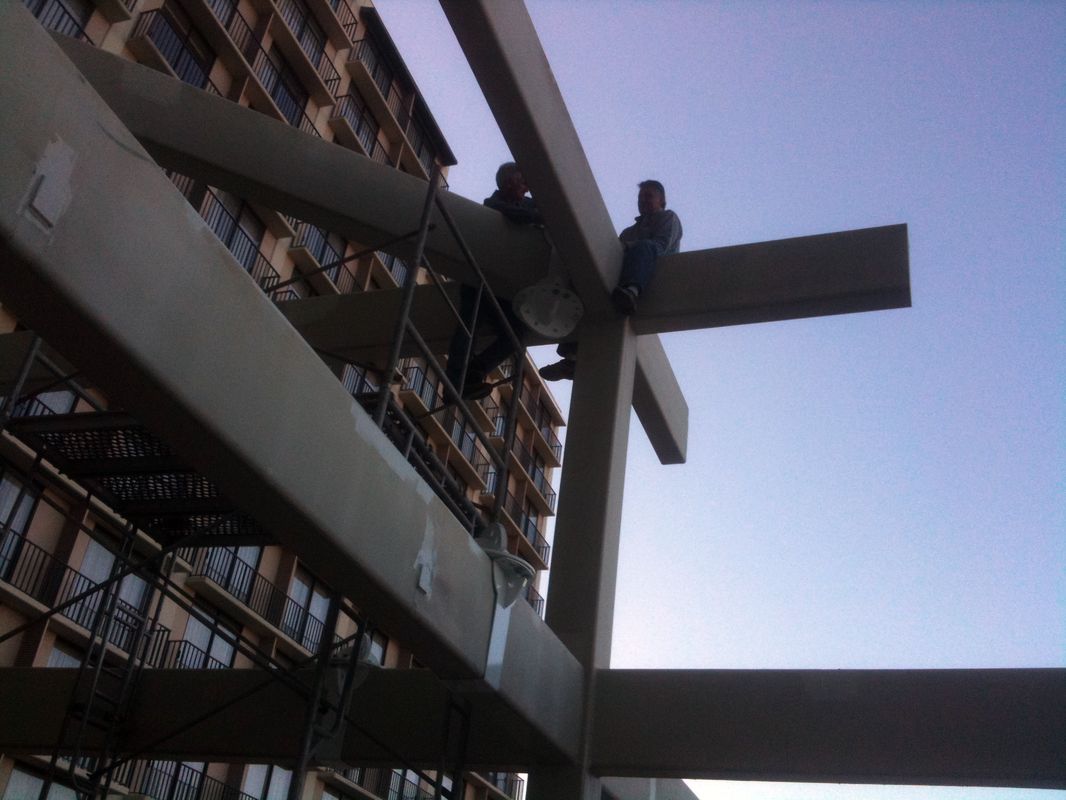 Steel beams and scaffolding at a construction site against a clear sky.