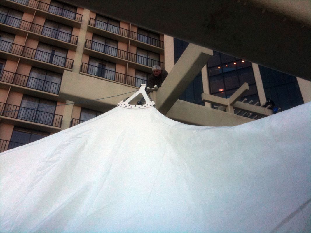 Close-up of a white tent structure with a building in the background.