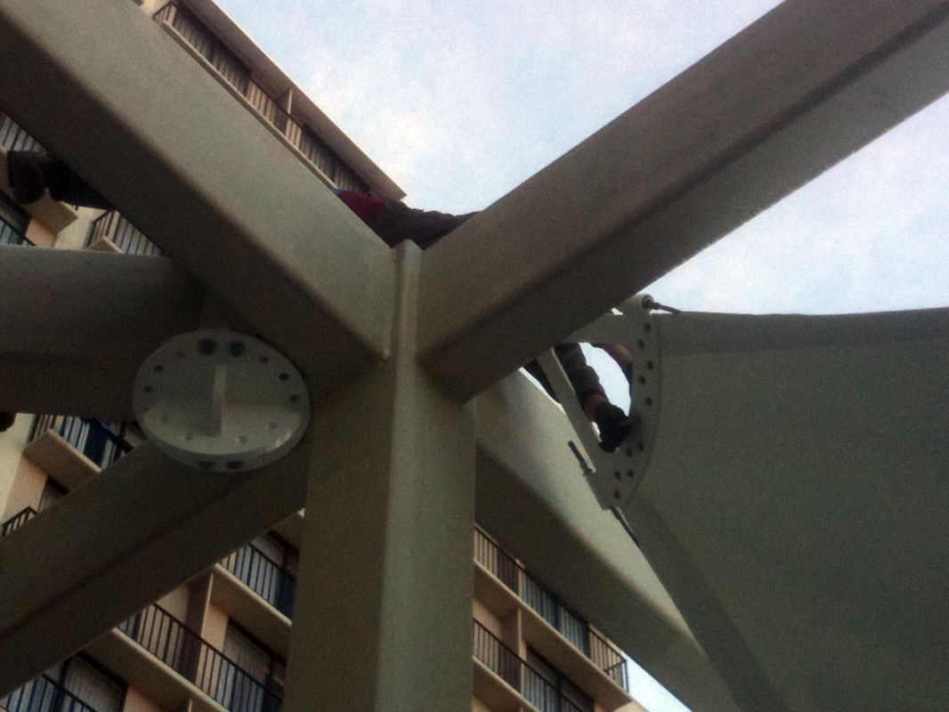 Clock mounted on an outdoor structure under a partly cloudy sky.