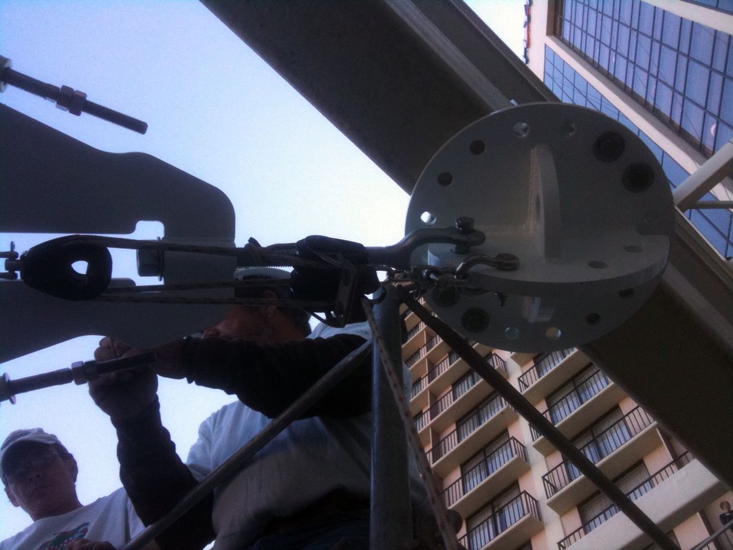 Person installing or adjusting a satellite dish on a building.