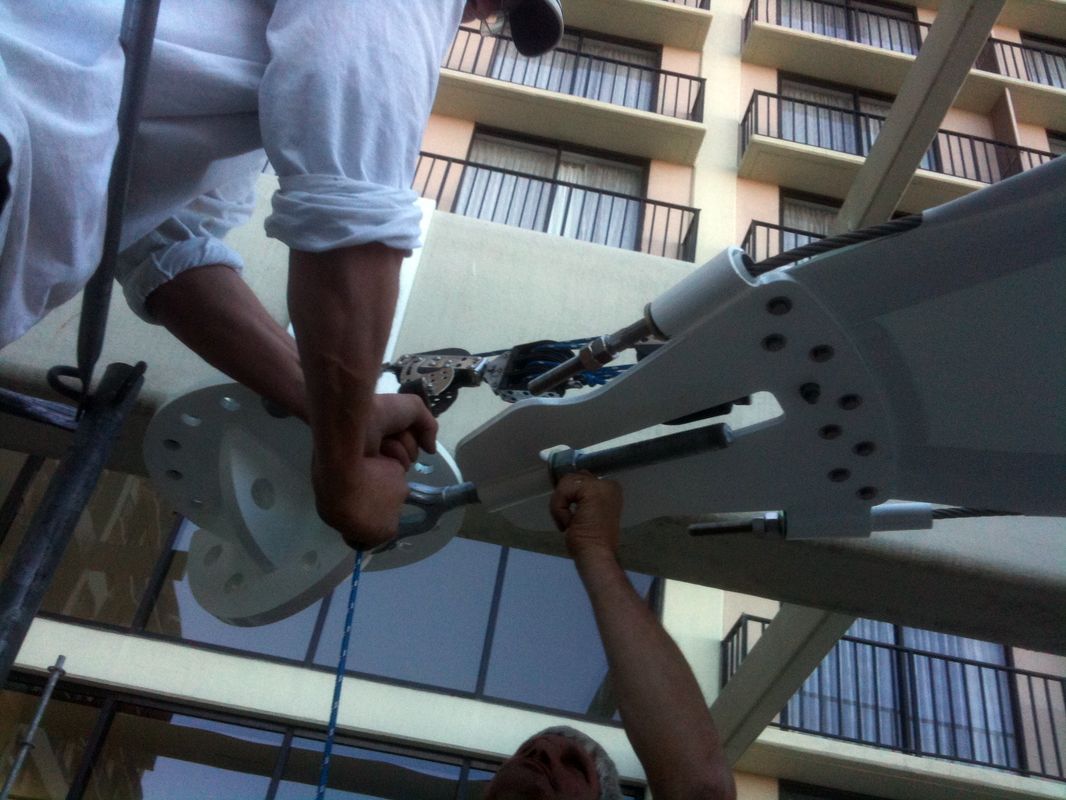 Two people adjusting a mechanical device outdoors near a building.