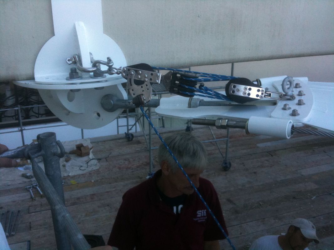 A man stands near a complex satellite dish setup at dusk.