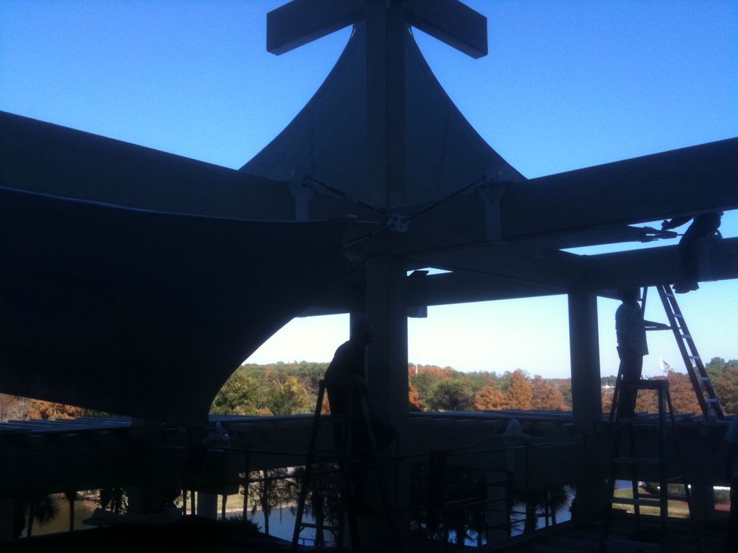 Silhouetted structure against a clear blue sky with a lake and trees in the background.