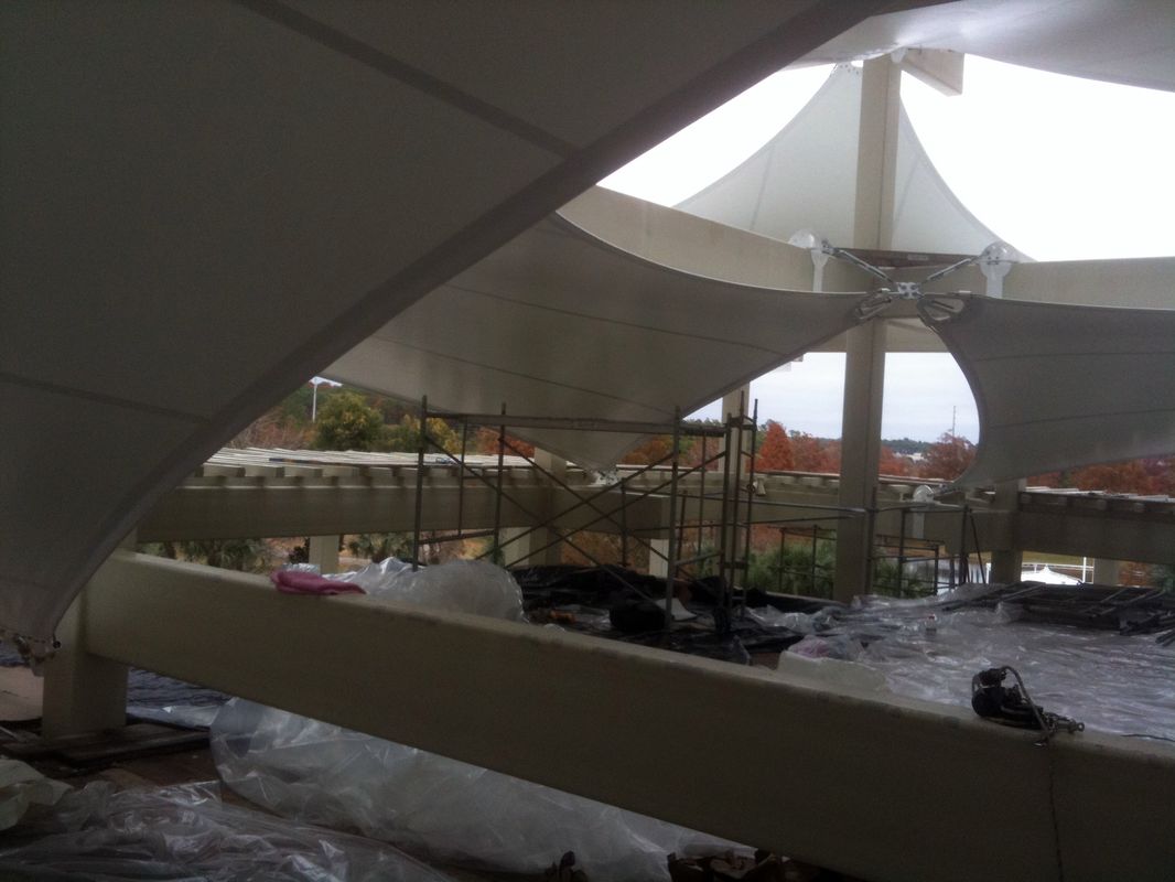 Construction site with curved concrete beams and scaffolding under a cloudy sky.