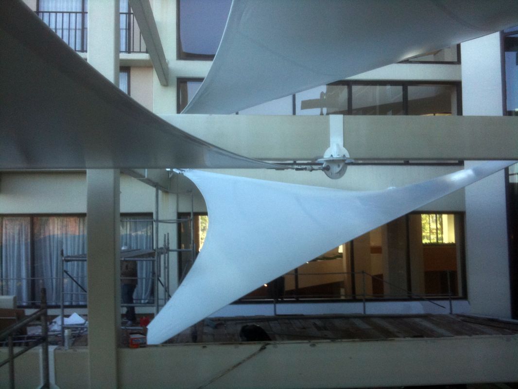 White triangular fabric shades stretched between buildings in an urban setting.