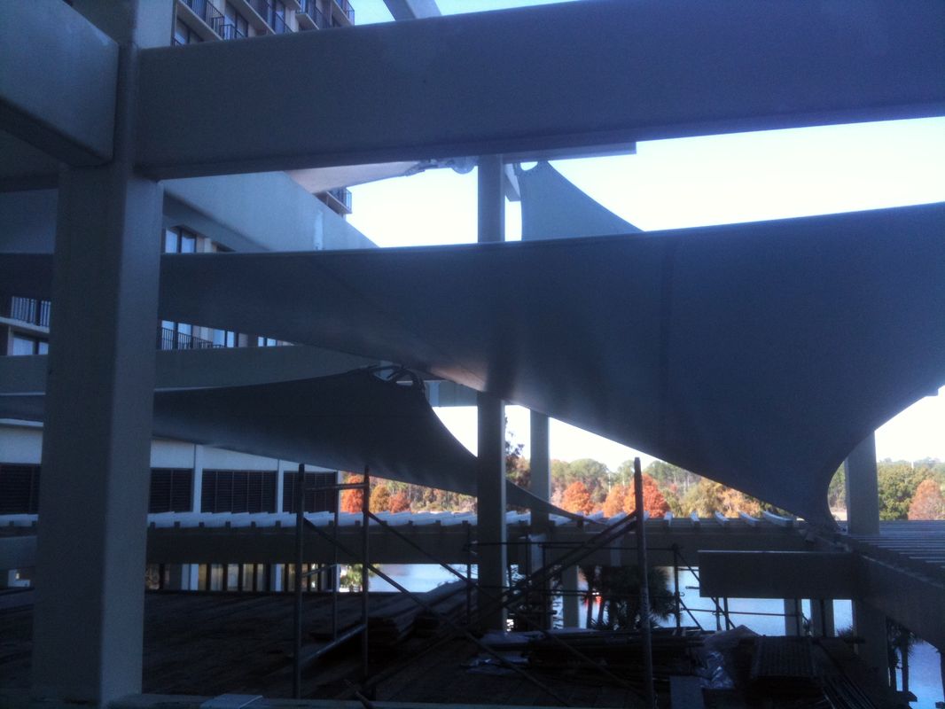 Construction site with steel beams and workers under a partly built structure.