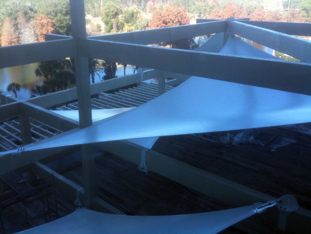 White triangular shade sails installed outdoors over a wooden deck.